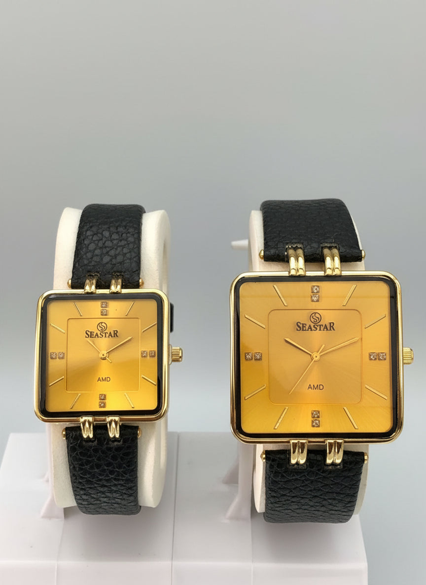 Gold square watch with black leather strap on a reflective surface